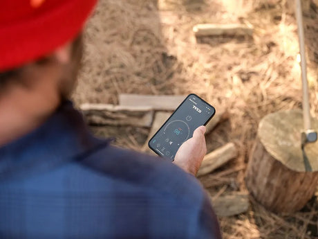 This is a lifestyle image showing a person controlling his sauna with an app on his phone.