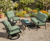 This is a lifestyle image showing this cushioned patio furniture set on a gravel patio in a backyard with lots of pretty and colorful flowers.