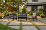 This is a lifestyle image showing this patio furniture set on a stone patio in a grassy backyard.