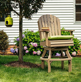 This is a lifestyle image showing the Weatherwood colored swivel Adirondack chair in a grassy garden on the side of a house.
