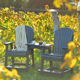 This is a lifestyle image showing two Coastal Gray and Black colored Adirondack chairs with a matching tete-a-tete table between them. 