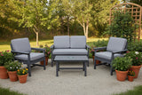 This is a lifestyle image showing this patio set on a gravel patio in a grassy midwestern backyard. The patio features potted plants and a trellis decorated with ivy.