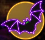 This image shows what this Halloween decoration looks like. It's designed to look like a purple bat with green eyes flying in front of a yellow moon.