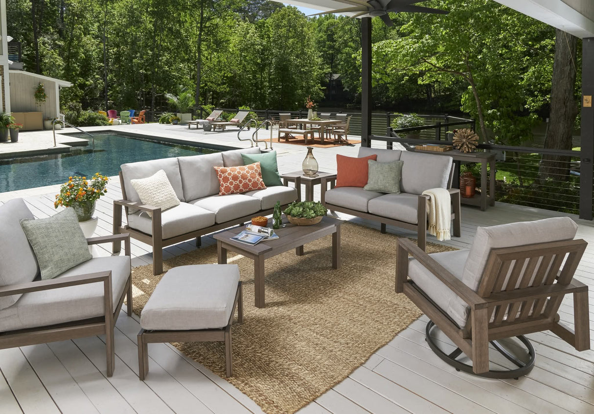 This is a lifestyle image showing this cushioned patio set on a wooden deck next to an in-ground pool.