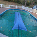 This is a lifestyle image showing the giant Pool Winterizing Pillow under a net cover on a large backyard pool.
