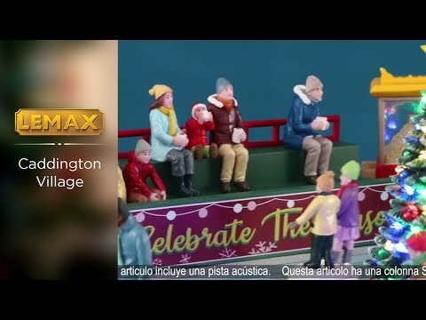 Polyresin, animated figure for a Lemax display. Designed to look like a small ice rink. There are a bunch of people skating around and there's a decorated Christmas tree in the middle of the rink. There's a food vendor, a green bench with people sitting and a popcorn vendor all behind the rink.