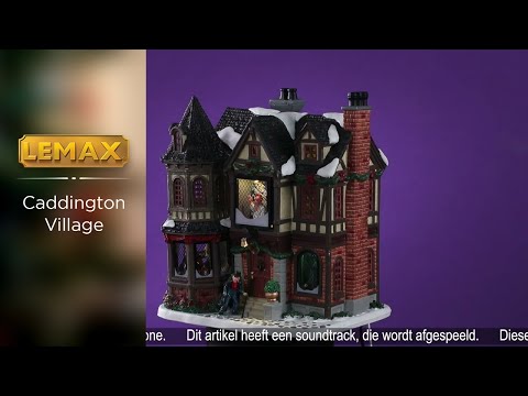 Lemax village building designed to look like an old Victorian style mansion covered in snow. There's green and red tinsel around the roof and some green bushes around the bottom. Scrooge is walking up the front steps.