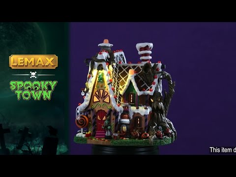 Resin lighted building for a Lemax display. Designed to look like a cabin made out of candy and frosting. There's a spooky tree growing on the side of the cabin and is also growing through the roof. There's a witch standing at the front door.