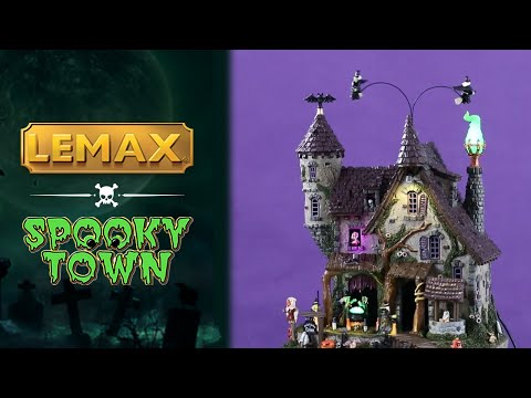 Resin lighted building for a Lemax display. Looks like a cottage with a moss covered tower. There are witches flying above and monsters and witches and a scarecrow and pumpkins.