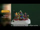Animated resin village accessory for a Lemax display. Designed to look like a family decorating a Christmas tree on a snowy patch. They're all wearing winter clothes. The kids are riding on reindeer that rock back and forth. There's also a dog watching, wearing a Santa hat. There's a pole nearby with a light on it.