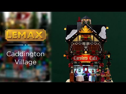Resin lighted building for a Lemax display. Designed to look like a tall, old-timey cottage decorated for Christmas. There's snow and a string of lights on the roof. There are carolers singing to people dining outside. There are garlands, red ribbons and a decorated Christmas tree.