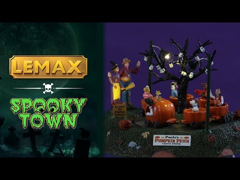 Resin table accent for a Lemax display. Designed to look like a carnival ride for kids. The carts are shaped like pumpkins. There are skull lights hanging from a bare tree and parents waving at their kids in the ride. There's a sign on the side that reads "ALL ABOARD THE PUMPKIN EXPRESS."