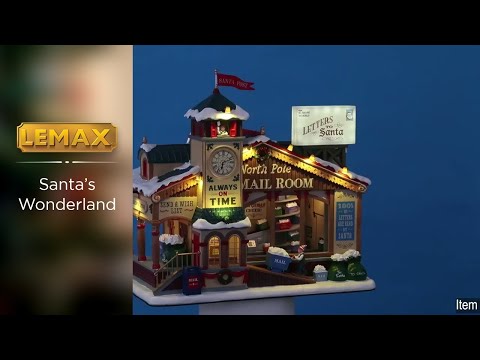 Polyresin lighted building for Lemax display. Designed to look like a wooden post office. There's a red flag on top of the roof that reads "Santa Post." There's a big sign that's shaped like an envelope that reads "Letters to Santa." There's a big clock and it reads "Always on time" underneath. Next to the clock it reads "North Pole Mail Room." There's an elf pushing a big cart of mail.
