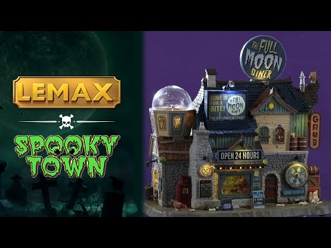 Resin lighted building for a Spooky Town Lemax display. Designed to look like a very large diner. There's a giant, circular sign on the roof that reads "THE FULL MOON DINER" and next to it is a round, yellow moon with a silhouette of a werewolf on it. There's a see through globe with a wolf inside and a werewolf eating inside the diner. There's garbage and bones on the sidewalk.