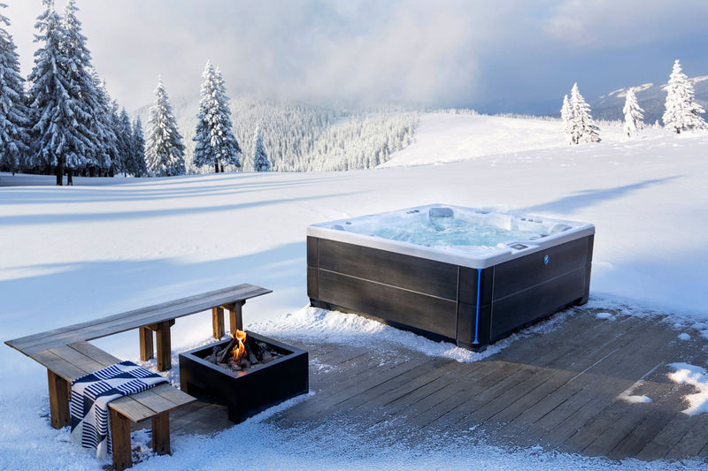 Hot tub and fire pit on a snowy deck with a mountainous background