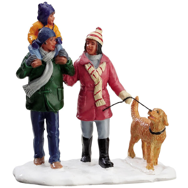 Village accent piece for a Lemax display. Designed to look like a mom and a dad walking a dog in the snow. There's a young child on the dad's shoulders. They're all wearing winter clothes and there's snow on the ground.