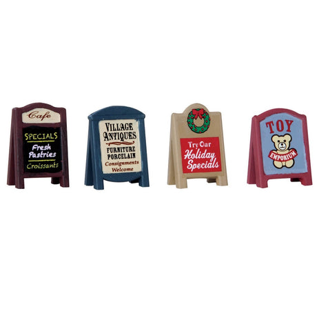 Village accessories for a Lemax display. Designed to look like a set of four sidewalk signs. One is for the specials at the cafe, advertising fresh pastries and croissants. Another is for village antiques, advertising porcelain furniture. Another has a wreath on it and reads "try our holiday specials." The last one is for the Toy Emporium.