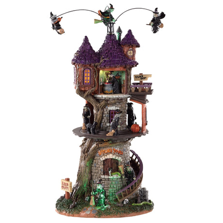 Polyresin tower for a Lemax display. Designed to look like a very large stone tower with a purple, pointed roof. There are witches circling the roof, a witch stirring a cauldron in the attic and witches sweeping the porch on the second level. There's a witch walking down the stairs to leave. There are snakes, skulls and tombstones on the ground. There's a sign that reads "KEEP OUT!"