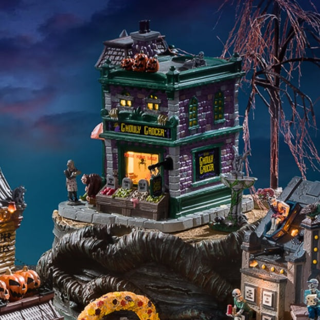 Porcelain lighted building for a Lemax display. Designed to look like a brick grocery store. There are monsters at the front door and boxes of stuff you can buy near the front window. Inside the window, you can see some creepy crawlies hanging from hooks. There are carved pumpkins on the roof.
