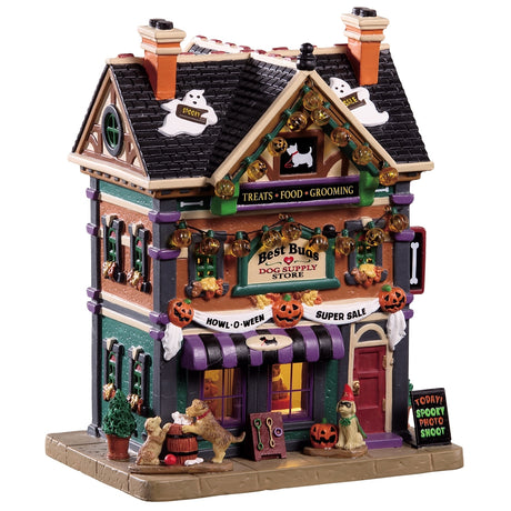Porcelain lighted building for a Lemax display. Designed to look like a large dog supply store decorated for Halloween. There are ghosts on the roof, pumpkin lights hanging from the roof and a sign with pumpkins that reads "HOWL-O-WEEN SUPER SALE." There are dogs playing in front of the store. There's a sign on the sidewalk that reads "TODAY! SPOOKY PHOTO SHOOT!"
