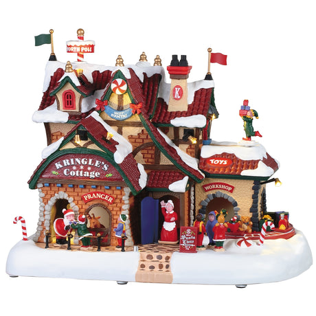 Polyresin lighted building for a Lemax Village display. The sign reads "Kringle's Cottage." Elves are everywhere making toys