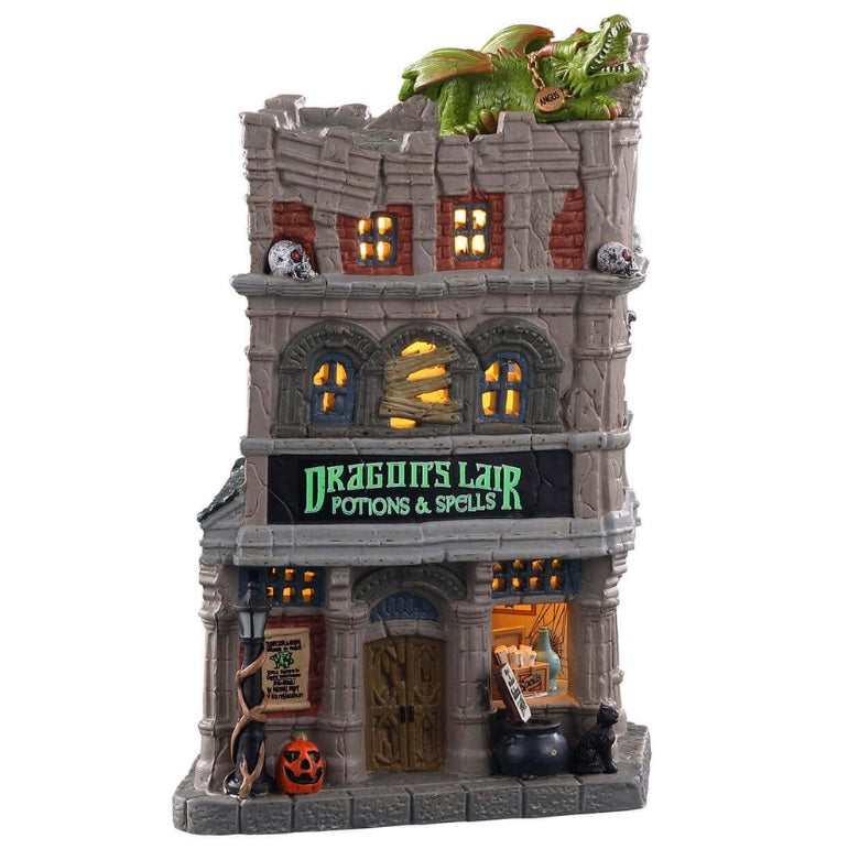 Porcelain lighted building for a Lemax display. Designed to look like a tall, old department store. The signs read "DRAGON'S LAIR POTIONS & SPELLS." There's a green monster on the roof. There are lampposts and a jack-o-lantern accent outside.
