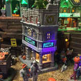 Porcelain lighted building for a Lemax display. Designed to look like a tall, old department store. The signs read "DRAGON'S LAIR POTIONS & SPELLS." There's a green monster on the roof. There are lampposts and a jack-o-lantern accent outside.