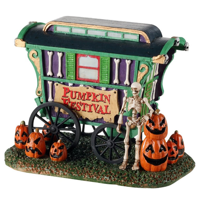 Polyresin village accent for a Lemax display. Designed to look like a green, purple and red cart that reads "PUMPKIN FESTIVAL." There are jack-o-lanterns on the ground and a skeleton standing next to the cart.