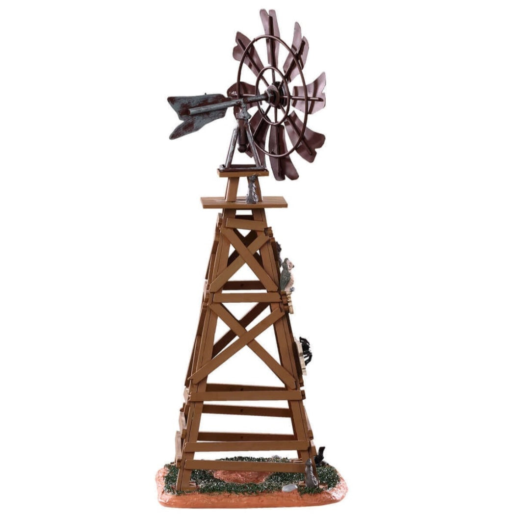 Polyresin table accent for a Lemax display. Designed to look like a wooden windmill with metal blades. There are two signs on it that read "DANGER!" and "BEWARE OF FALLING BLADES!" The danger sign has a small owl sitting on it. The beware sign has a big, black spider on it. There's a little bit of grass and dirt on the ground underneath it. There's a small rat standing at the bottom.