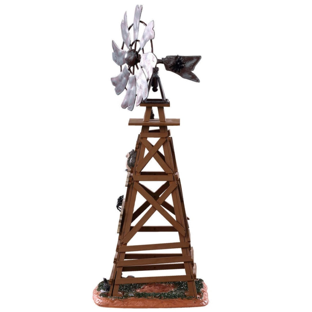 Polyresin table accent for a Lemax display. Designed to look like a wooden windmill with metal blades. There are two signs on it that read "DANGER!" and "BEWARE OF FALLING BLADES!" The danger sign has a small owl sitting on it. The beware sign has a big, black spider on it. There's a little bit of grass and dirt on the ground underneath it. There's a small rat standing at the bottom.