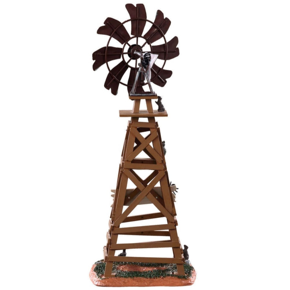 Polyresin table accent for a Lemax display. Designed to look like a wooden windmill with metal blades. There are two signs on it that read "DANGER!" and "BEWARE OF FALLING BLADES!" The danger sign has a small owl sitting on it. The beware sign has a big, black spider on it. There's a little bit of grass and dirt on the ground underneath it. There's a small rat standing at the bottom.