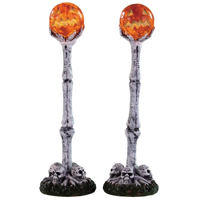 Polyresin village accents for a Lemax display. Designed to look like two lampposts made of bones and skulls. The lights look like carved pumpkins.