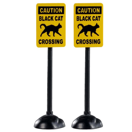 Plastic village accessories for a Lemax display. Designed to look like two yellow signs that read "CAUTION: BLACK CAT CROSSING" and has a cartoon picture of a black cat on it.