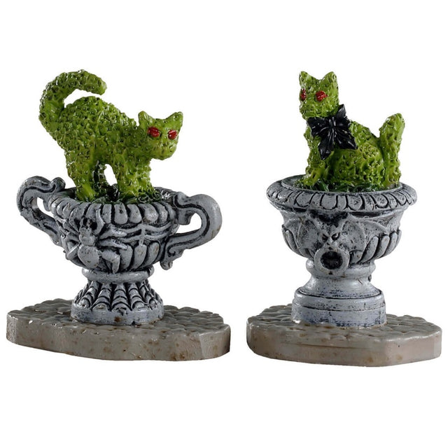 Polyresin village accents for a Lemax display. Designed to look like green bushes that have been trimmed to look like cats. One of the bushes is in a pot that has a spider on it. The other bush is in a pot that has a bat on it.