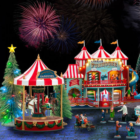 A Lemax display consisting of the Christmas Cheer Carousel and a Circus Funhouse. There are a few lighted trees and a bunch of people doing various activities off to the side. The display mat underneath it all is designed to look like a stone walkway. There are fireworks in the sky.