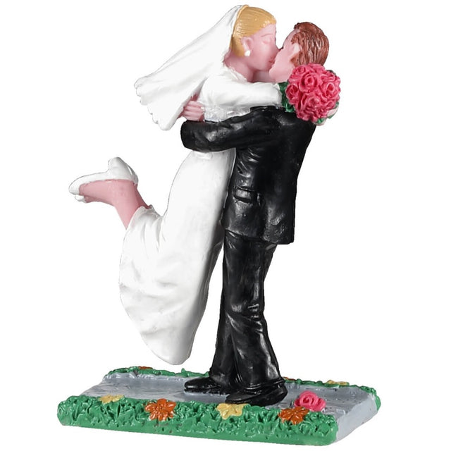 Polyresin figurine for a Lemax Village tabletop display. Designed to look like a bride and a groom kissing on a sidewalk with grass and flowers on both sides