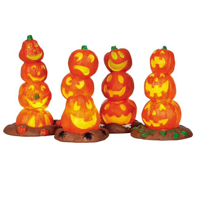 Plastic village accessories for a Spooky Town Lemax display. Designed to look like four stacks of pumpkins that are carved into different faces. One stack of pumpkins has smaller pumpkins on the ground underneath it. One stack of pumpkins has spiders on the ground underneath it. One stack of pumpkins has rocks underneath it. One stack of pumpkins has leaves underneath it.