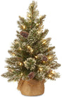 A small tabletop tree in a burlap base. The branches are covered in white glitter. There are warm white lights and pine cone accents.
