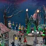 A Lemax display designed to look like a cemetery with bare trees, tombstones, statues, skeletons dancing and a Dia De Los Muertos vigil.