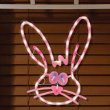 A pink window silhouette decoration for Easter. Designed to look like a cute bunny head with blue eyes and a red nose
