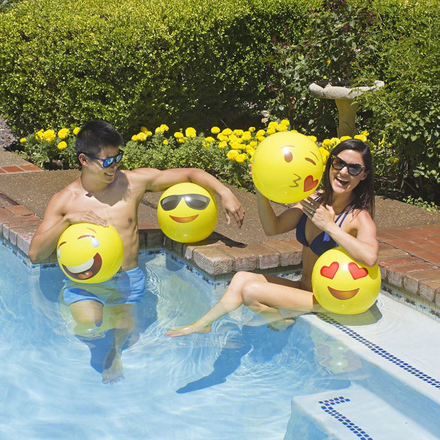 Yellow beach balls designed to look like different emojis.