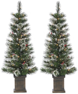 2 potted artificial trees. The tree tips are white to look like snow. The lights are warm white and there are red berry accents.