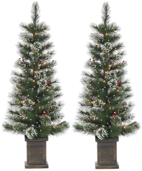 2 potted artificial trees. The tree tips are white to look like snow. The lights are warm white and there are red berry accents.