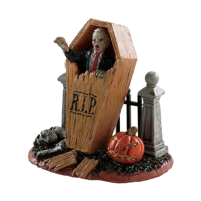 Polyresin figure for a Lemax display. Designed to look like a zombie breaking out of a coffin. The coffin is leaning up against a black metal fence with gray columns. There's a carved jack-o-lantern on the ground.