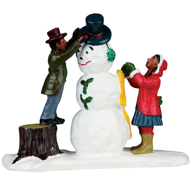 Polyresin figurine for a Lemax display. Designed to look like two people decorating a snowman. One of them is standing on a stump to put a top hat on the snowman's head.