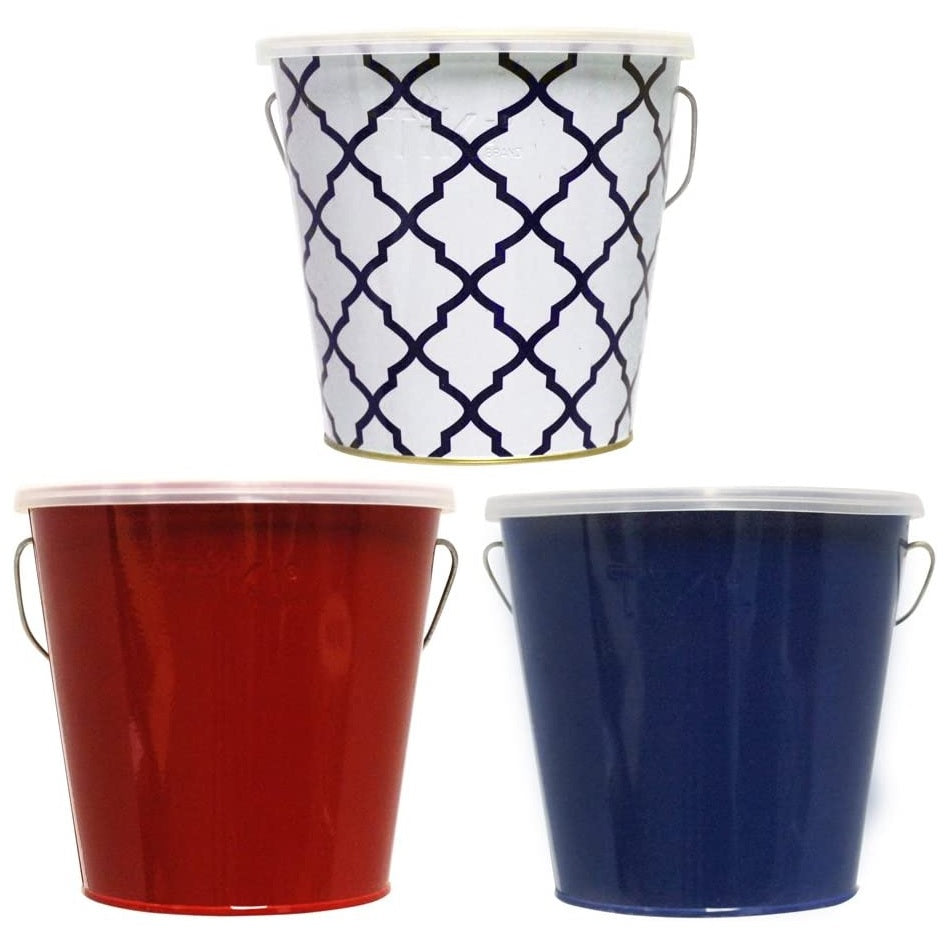 This picture shows the different color options for these TIKI candles. One candle is in a white and blue tin bucket. One candle is in a shiny, red tin bucket. The other candle is in a shiny, blue tin bucket.