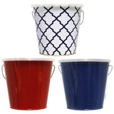 This picture shows the different color options for these TIKI candles. One candle is in a white and blue tin bucket. One candle is in a shiny, red tin bucket. The other candle is in a shiny, blue tin bucket.
