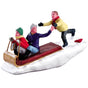 Polyresin figurine for a Lemax display. Designed to look like a young boy chasing after his two friends in a toboggan. They're all wearing winter clothes and the ground is covered in snow.