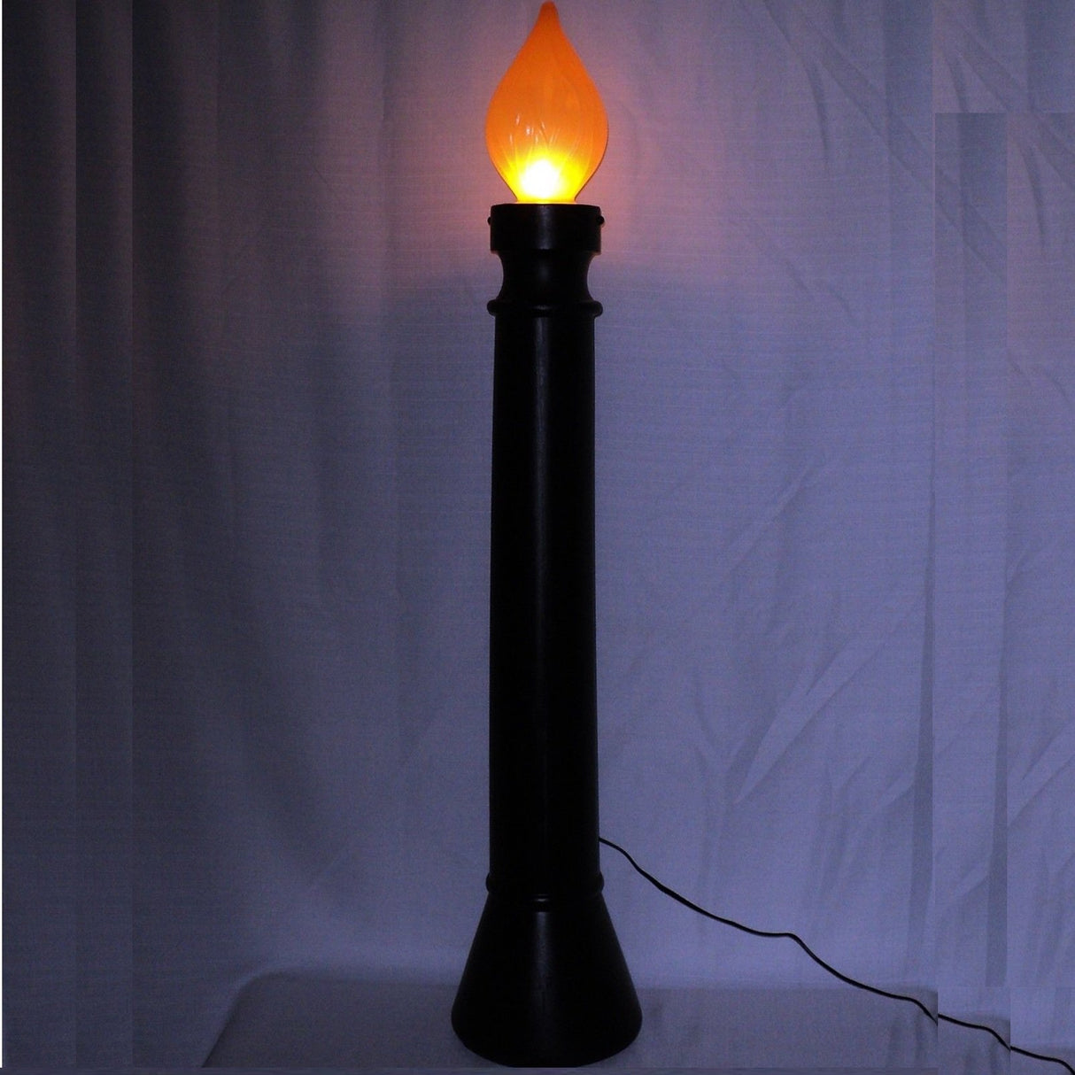 Black blow mold candle with orange flame. Flame lights up.