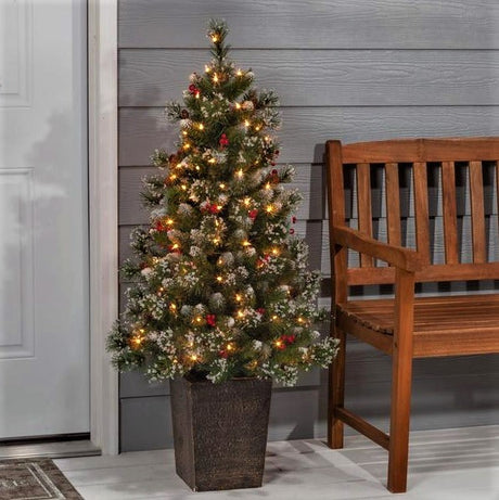 Potted artificial tree. The tree tips are white to look like snow. The lights are warm white and there are red berry accents.